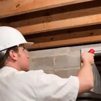 Termite inspection technician checking a basement wall and framing for termite activity in {city}, {state}